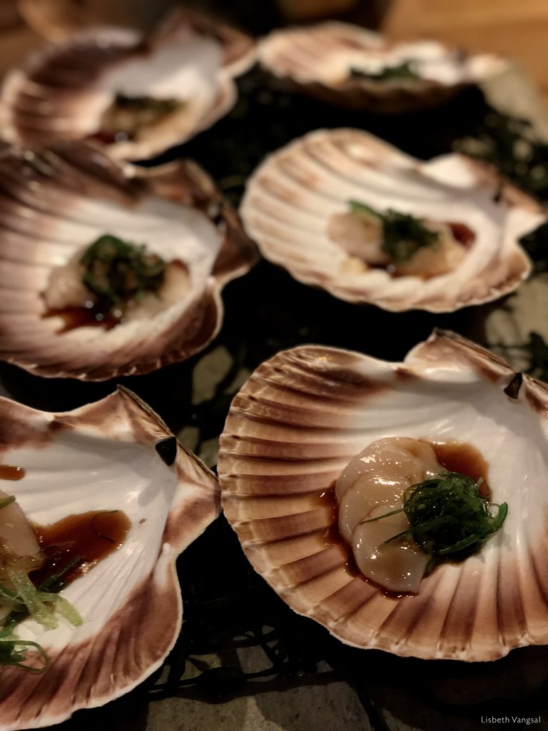 Kamskjell servert i skjell med urter